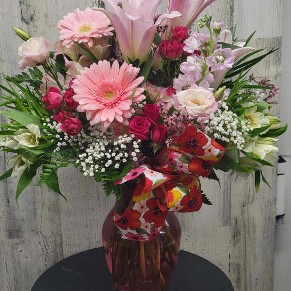 Pink mixed bouquet in a glass vase with a floral ribbon