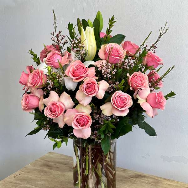 Pink roses and white lilies arranged in a clear glass vase