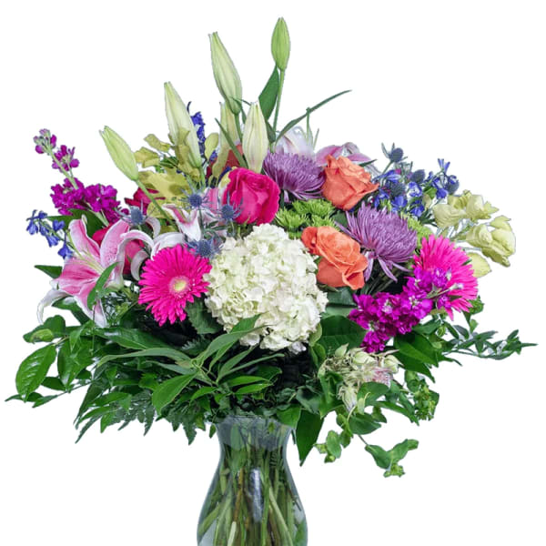 Mixed bouquet of lilies, roses, and daisies in a glass vase