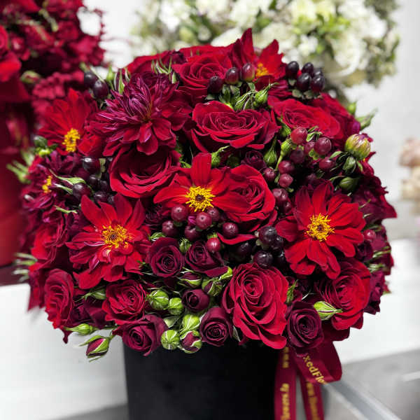 Red roses and burgundy flowers arranged in a black box