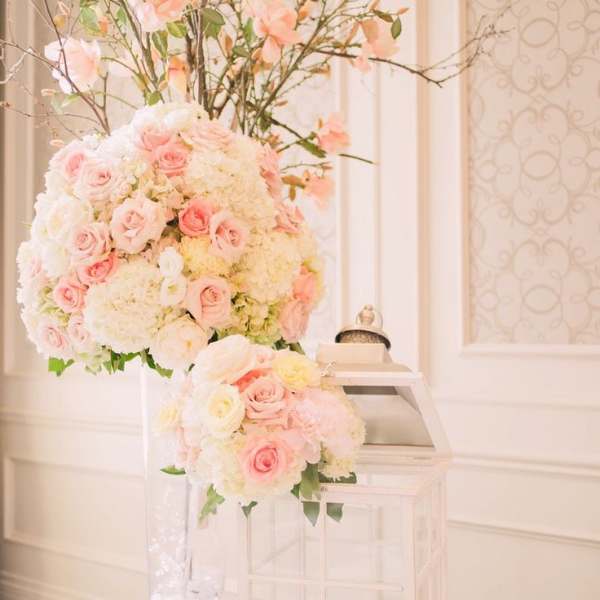 Tall pastel floral arrangement with pink roses and white blooms in a clear vase