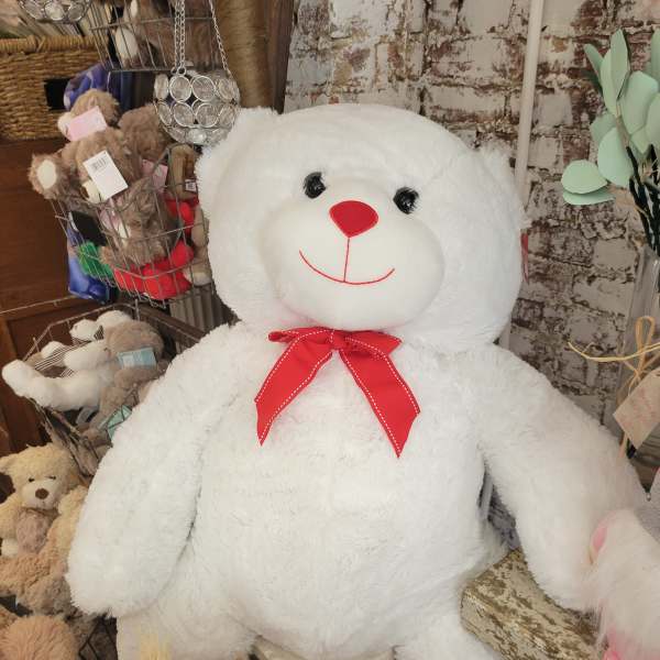 Large white teddy bear with a red bow tie