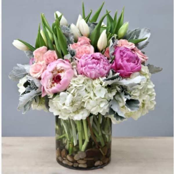Pink and white flowers arranged in a glass vase with pebbles