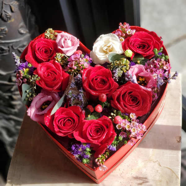 Heart-shaped box of red and pink roses with white blooms