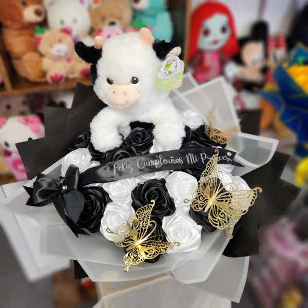 Plush cow on a bouquet of black and white roses with butterfly decorations