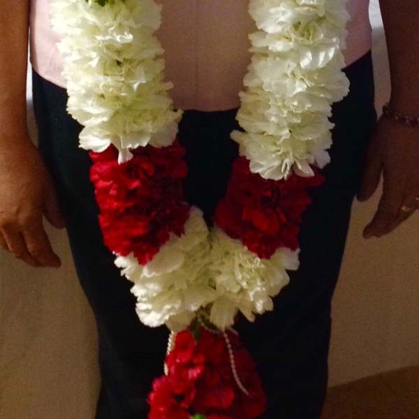 Person wearing long white and red flower garlands around the neck