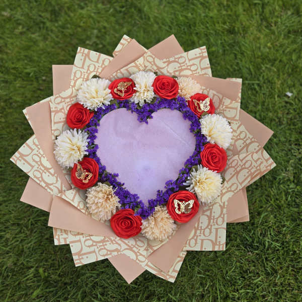 Heart-shaped bouquet with red roses and white blooms on pink wrapping