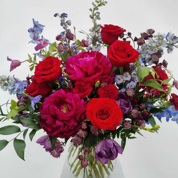 Bouquet of red roses and purple flowers in a clear glass vase
