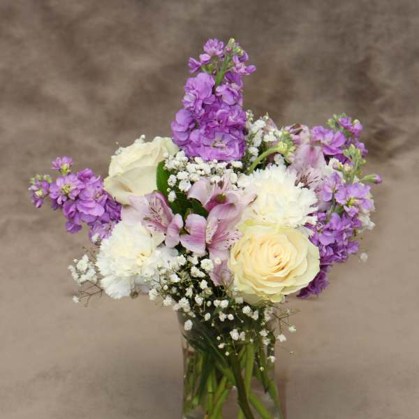 Bouquet of purple and white flowers in a clear glass vase