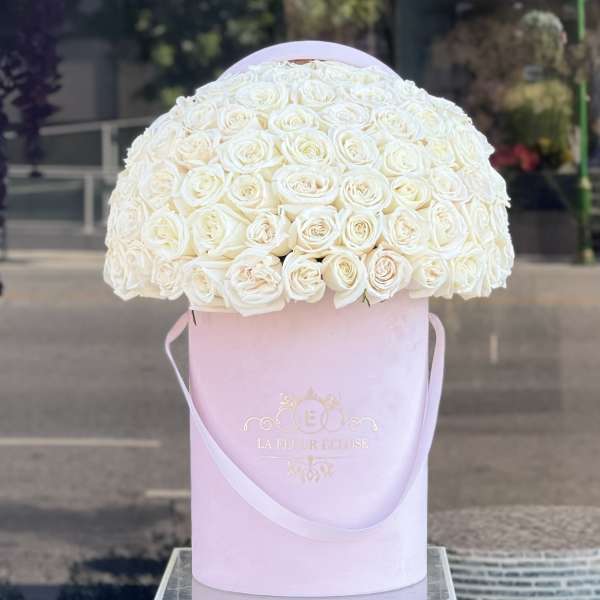White rose bouquet in a pink hat box with ribbon handles