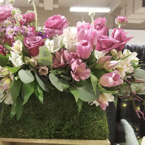 Pink and white floral arrangement in a moss-covered rectangular container