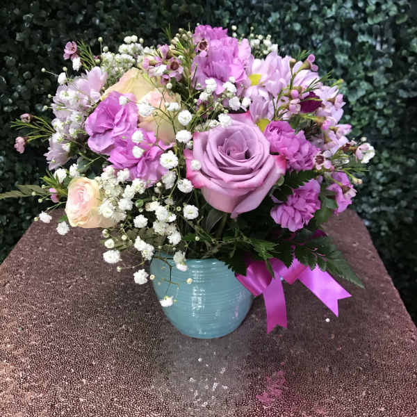 Pink and lavender bouquet in a blue vase with a ribbon