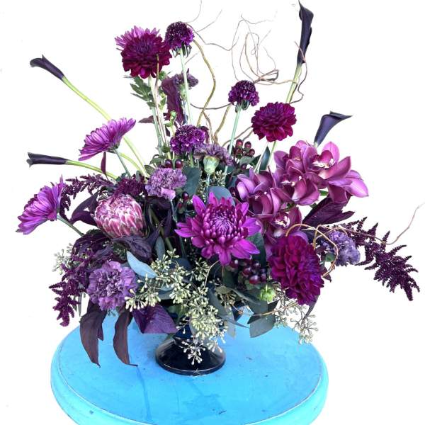 Purple floral arrangement with orchids and calla lilies in a black vase
