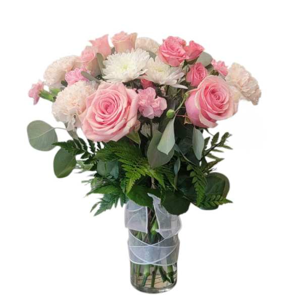 Pink roses and white flowers in a clear glass vase with ribbon
