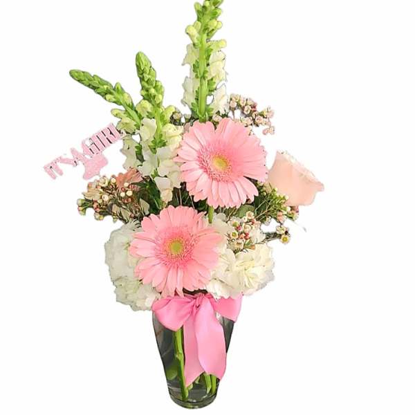 Pink gerbera daisies and white flowers in a glass vase with a pink ribbon