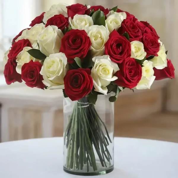 Arrangement of red and white roses in a clear glass cylinder vase
