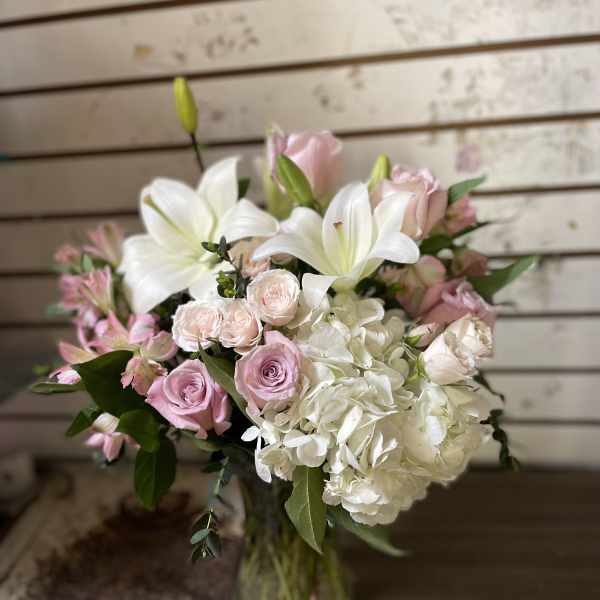 Pink and white bouquet with lilies, roses, and hydrangea in a glass vase
