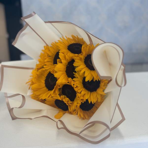 Bouquet of sunflowers wrapped in cream paper with brown trim