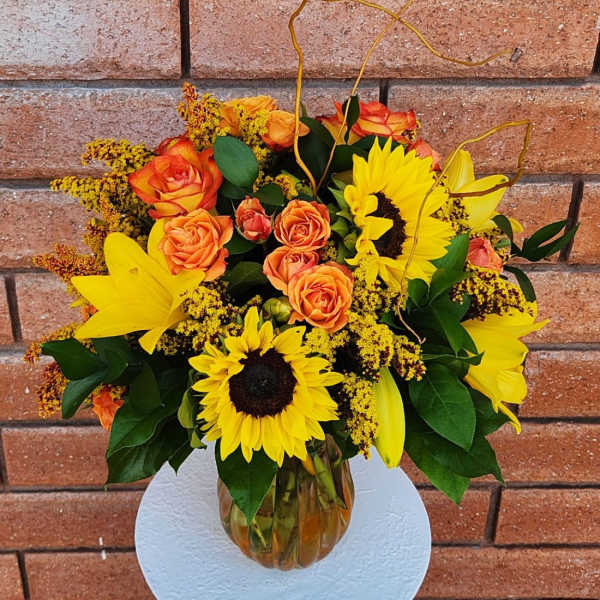 Bouquet of yellow sunflowers and orange roses in a glass vase