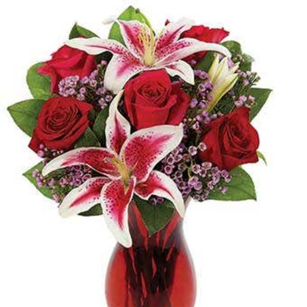 Red roses and pink lilies in a red glass vase