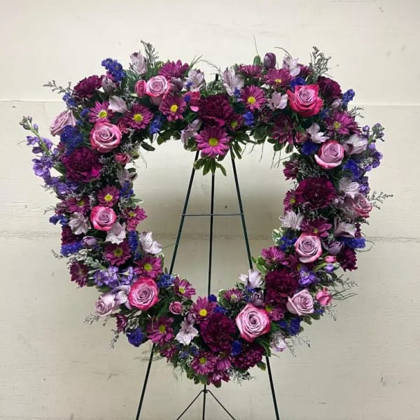 Heart-shaped standing wreath of pink and purple flowers on a metal easel