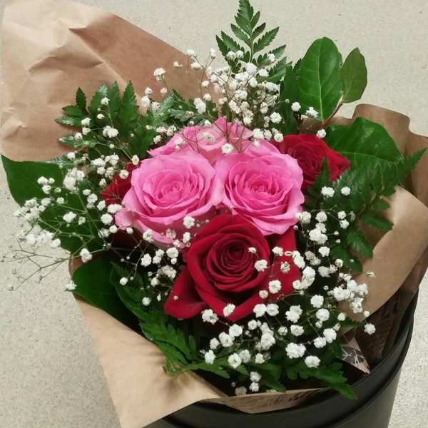Bouquet of pink and red roses with baby's breath in brown paper