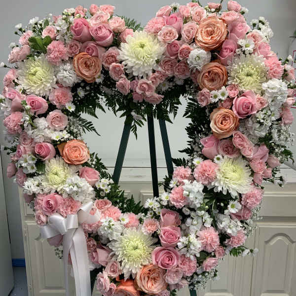 Heart-shaped floral wreath with pink and white flowers on an easel