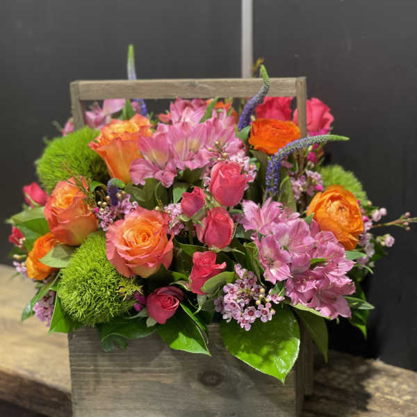 Bright pink and orange roses with green blooms in a rustic wooden box.
