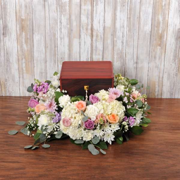 Cremation urn surrounded by a low wreath of white and pastel flowers