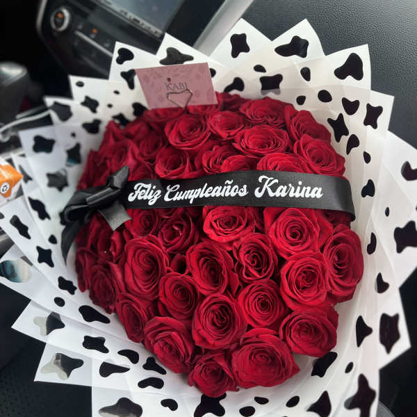Heart-shaped bouquet of red roses with black-and-white wrap and ribbon
