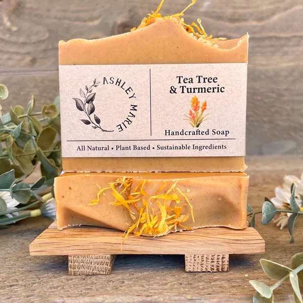 Two bars of tea tree and turmeric soap on a small wooden stand