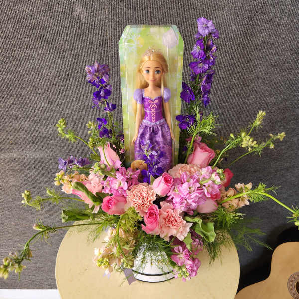 Princess doll in a pink and purple flower arrangement