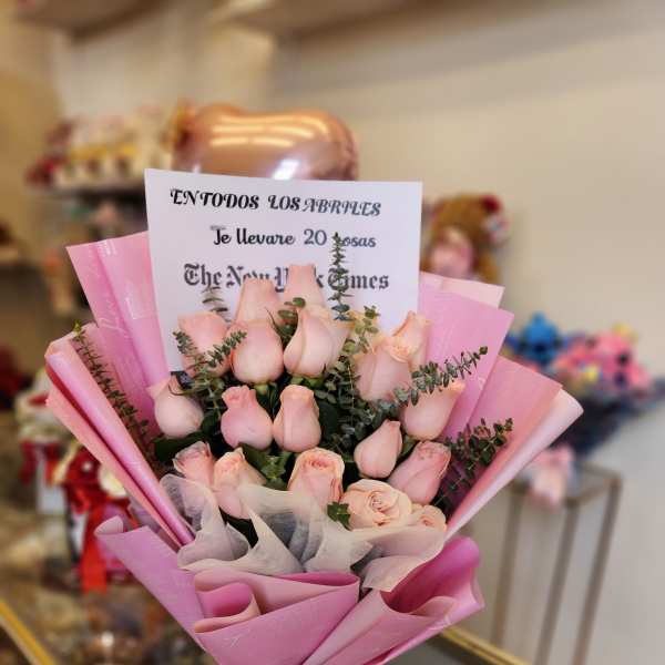 Bouquet of pale pink roses wrapped in pink paper with a ribbon