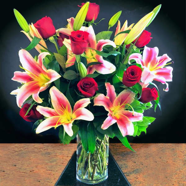 Bouquet of red roses and pink lilies in a clear glass vase