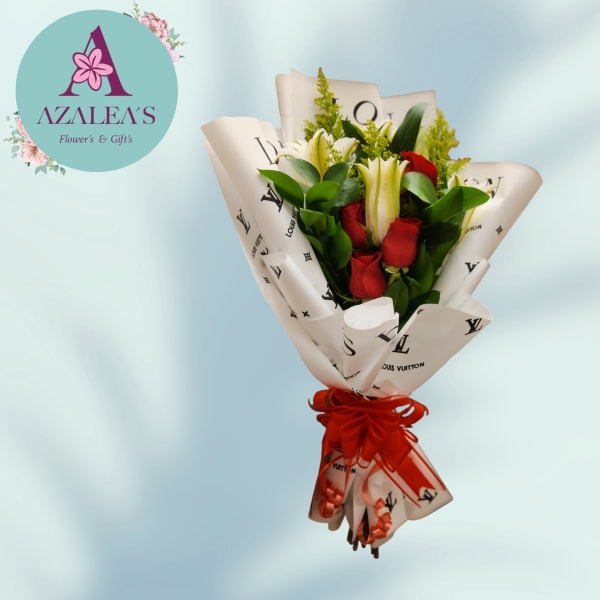 Bouquet of red roses and white lilies wrapped in printed paper with a red ribbon