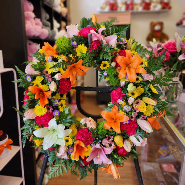 Colorful floral wreath with lilies and mixed blooms on a stand