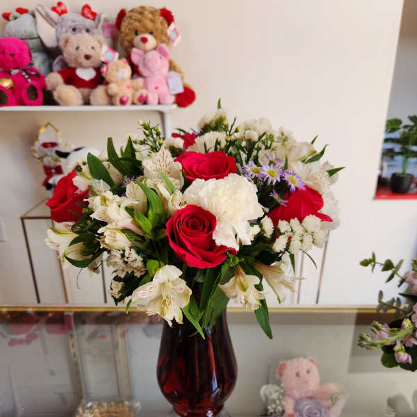 Bouquet of red roses and white flowers in a dark glass vase