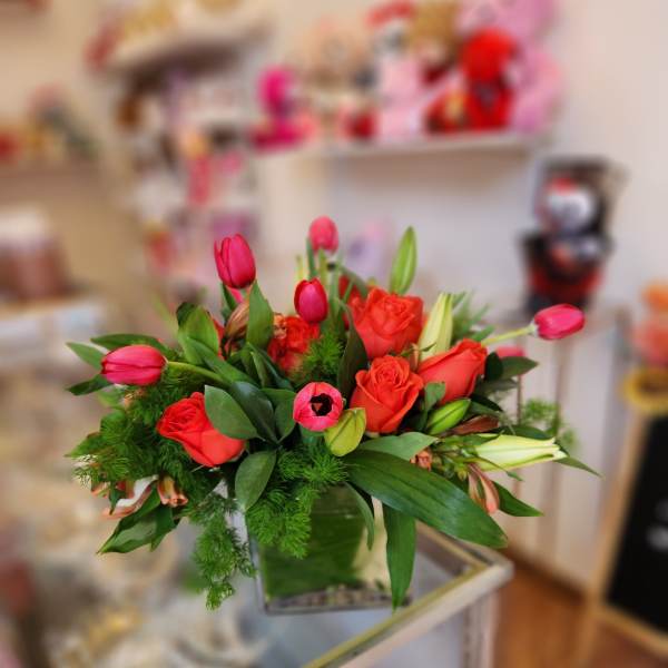 Bouquet of red roses and pink tulips in a glass vase