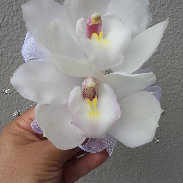 Handheld corsage with two white orchid blooms and a pale ribbon