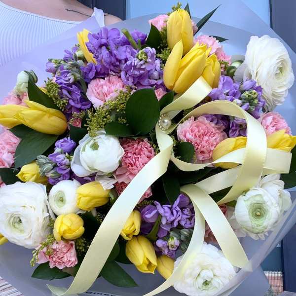 Bouquet of yellow tulips, purple stock, pink carnations, and white ranunculus