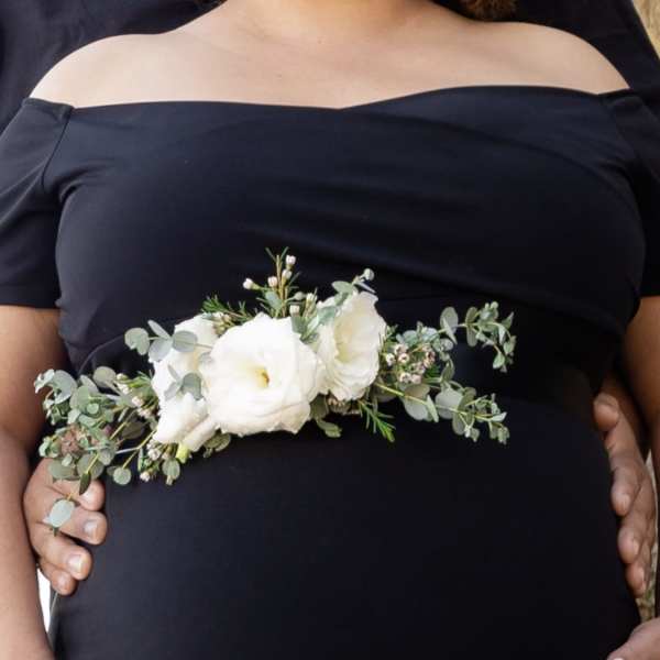 White floral corsage with greenery worn at the waist