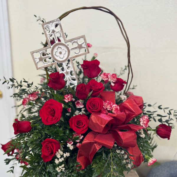Red roses arranged with a decorative cross and ribbon