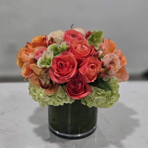 Pink and orange rose arrangement in a dark glass vase