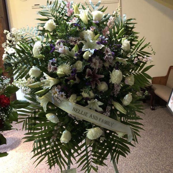 Large funeral spray of white lilies and mixed flowers with a ribbon