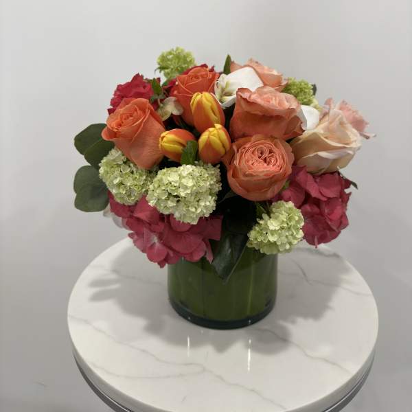 Mixed bouquet of roses, tulips, and hydrangeas in a green vase