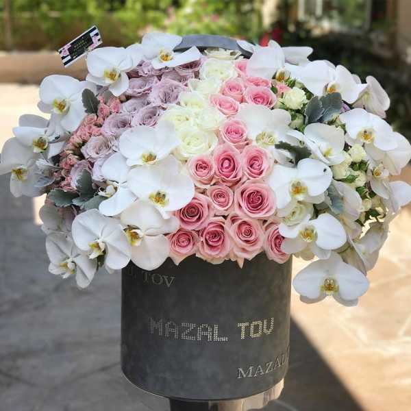 Pink and white roses with white orchids in a black hat box