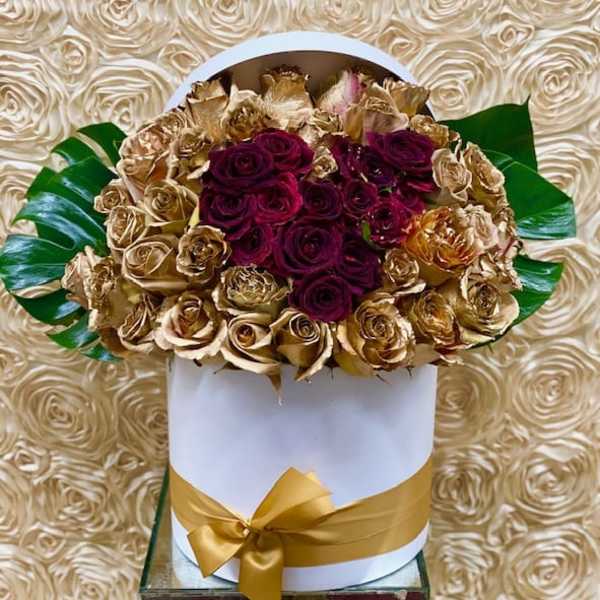 Bouquet of deep red and gold roses in a white hat box with a gold ribbon