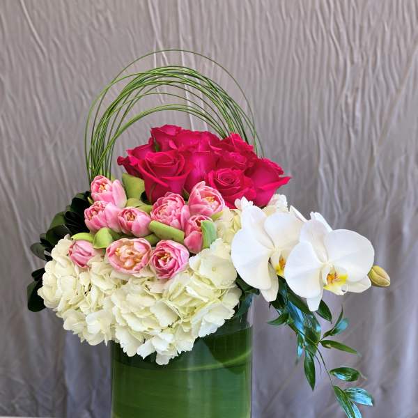 Pink roses, white hydrangeas, and white orchids in a green vase