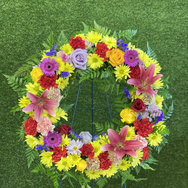 Colorful floral wreath with lilies, roses, and daisies on a stand