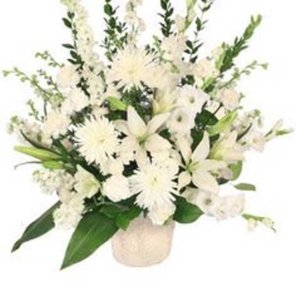 All-white arrangement of lilies, mums, and other flowers in a textured white container